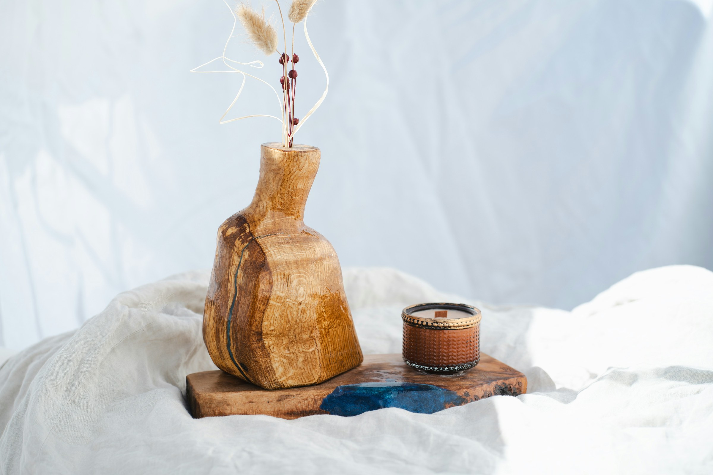 Holzvase mit Trockenblumen und kleinem Gefäß auf einem Tablett