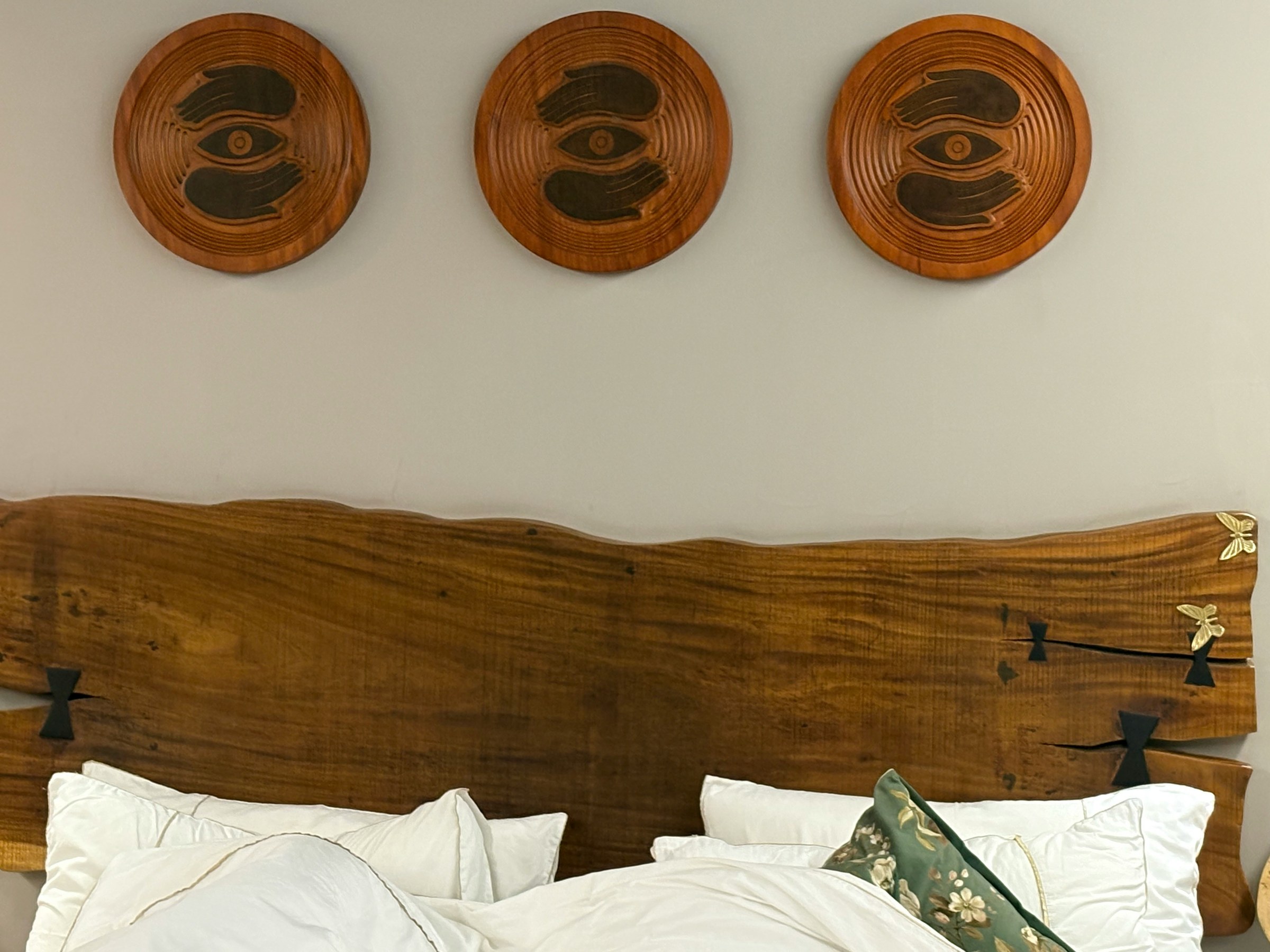 Schlafzimmer mit breitem Holzkopfteil und runden Wandobjekten aus Holz